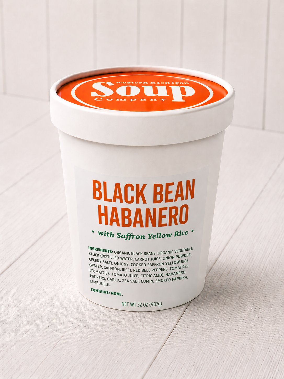 Container of Black Bean Habanero soup with saffron yellow rice on a light wooden surface.