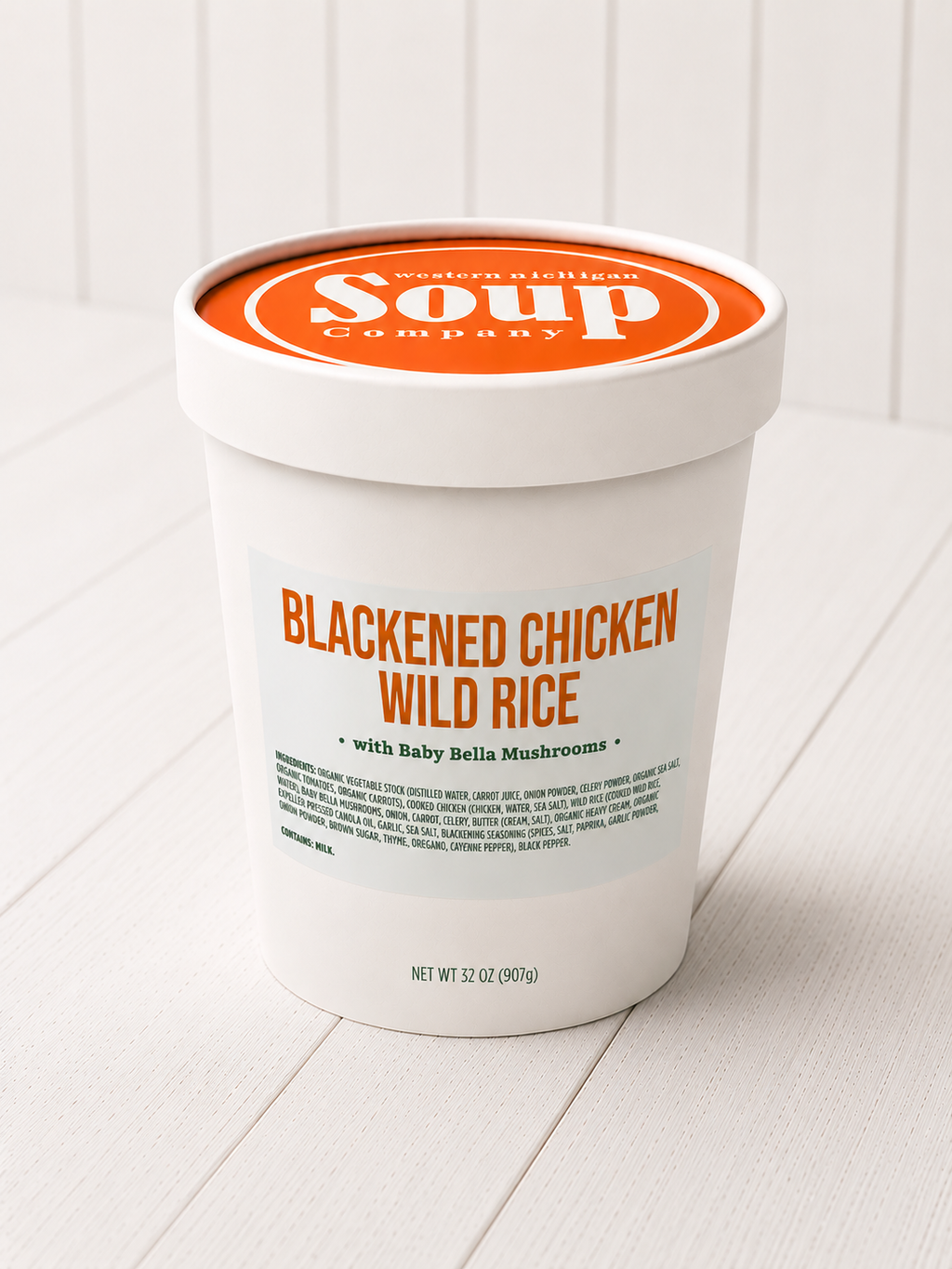 Container of Blackened Chicken Wild Rice soup from the WISoup Company on a white wooden surface.