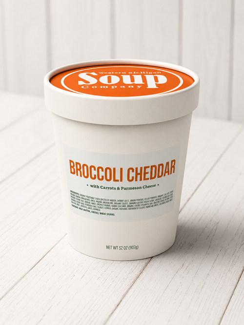 Container of broccoli cheddar soup from the WISoup Company on a white wooden surface.