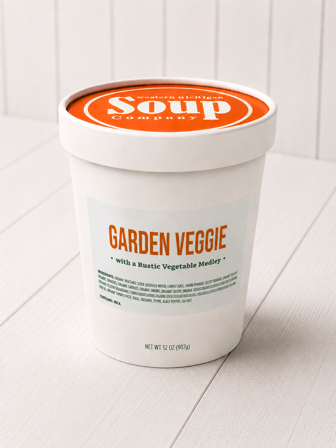White container of 'Garden Veggie' soup with orange label on a white wooden surface