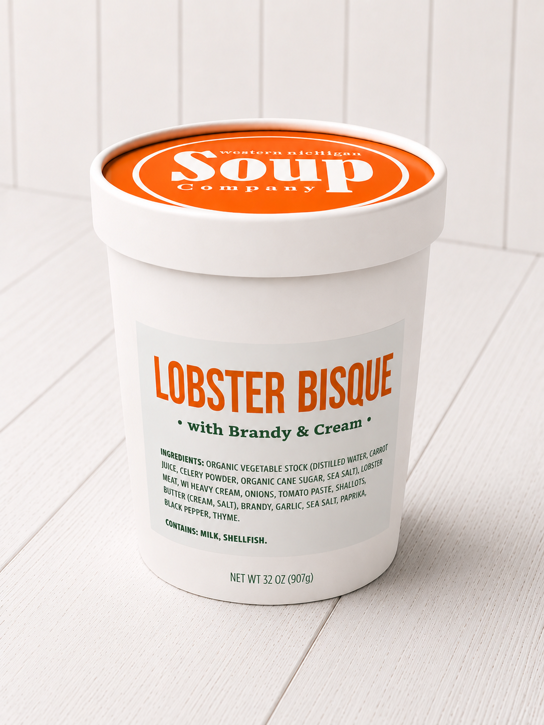 Container of lobster bisque soup with brandy and cream on a white background