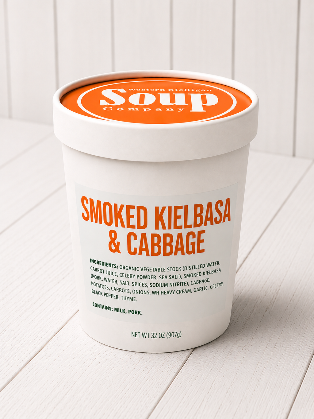 Container of 'Smoked Kielbasa & Cabbage' soup from the WISoup Company on a white wooden surface.