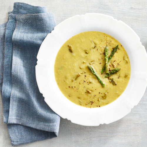 Creamy asparagus soup served with roasted asparagus tips and blue napkin