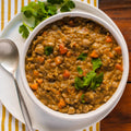 A bowl of curry lentil soup with chickpeas, basmati rice, and diced vegetables, garnished with fresh cilantro.